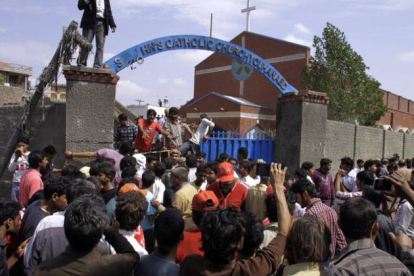 Los cristianos paquistanís y los equipos de rescate se reúnen fuera de una iglesia dañada por un ataque suicida.-Foto: K.M. CHAUDARY / AP