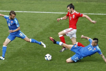 Bale conduce el balón perseguido por dos rivales en el partido inaugural de Gales.-HASSAN AMMAR / AP