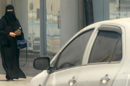 Una mujer saudí camina junto a un coche en una calle de Riad, la capital de Arabia Saudí, el 27 de septiembre.-AFP / FAYEZ NURELDINE