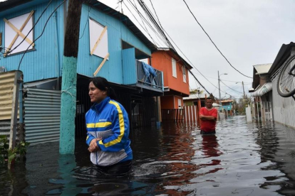 Dos personas caminan por una calle inundada en Juana Matos (Puerto Rico), el 21 de septiembre-AFP / HECTOR RETAMAL