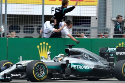 Hamilton celebra el triunfo en Alemania al paso frente a sus mecánicos.-AFP / THOMAS KIENZLE