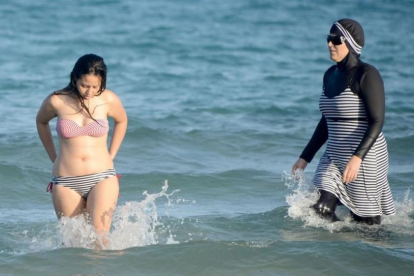 Una mujer con biquini y otra con 'burkini' en la playa tunecina de Ghar El Melh.-AFP / FETHI BELAID
