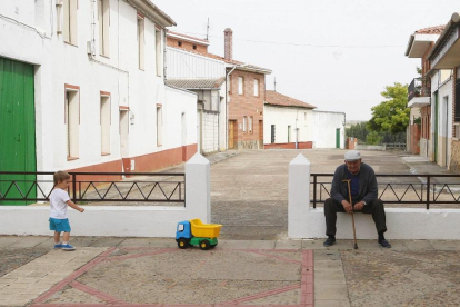 Un pequeño juega junto a una persona mayor en la localidad vallisoletana de Mayorga.