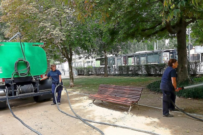 Dos trabajadoras municipales riegan los jardines del Poniente con el agua de un camión cistena.-E. M.