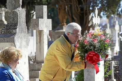 Un hombre deposita un centro de flores sobre una de las lápidas en la víspera del Día de Todos los Santos.-J.M.LOSTAU