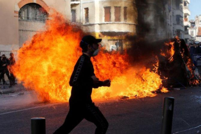 Unos jóvenes queman contenedores de basura en Marsella durante una manifestación contra los planes fiscales del Gobierno francés.-JEAN-PAUL PELISSIER (REUTERS)