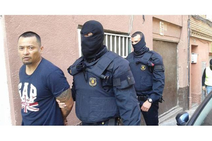 Imagen cedida por la Cadena Ser, en la que dos mossos se llevan detenido, en Santa Coloma de Gramenet, a uno de los presuntos miembros de la banda de Latin Kings desarticulada este miércoles.-Foto: CADENA SER