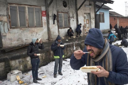 Refugiados comen en el exterior de un almacén abandonado en Belgrado.-MSF / MARKO DROBNJAKOVIC