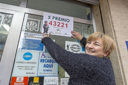 Carmen Lino pega el cartel del premio en su copistería del barrio de Pajarillos.-Miguel Ángel Santos