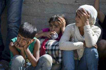 Tres refugiados sirios descansan en el arcen de la carretera de Presevo, en Serbia.
MARKO DJURICA / REUTERS