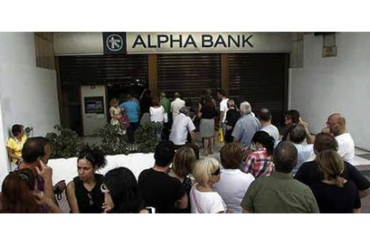Decenas de personas hacen cola para sacar dinero de un banco en Atenas.-ALEXANDROS VLACHOS / EFE