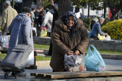 Una anciana sintecho recoge sus pertenencias en Atenas.-LOUISA GOULIAMAKI
