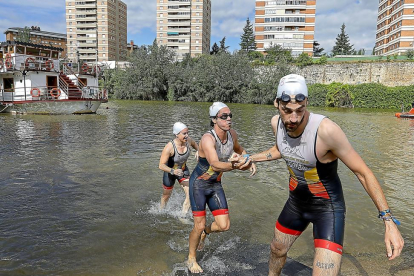 Un triatleta del Tetuán ayuda a salir del agua a su compañera de equipo.-J.M.LOSTAU