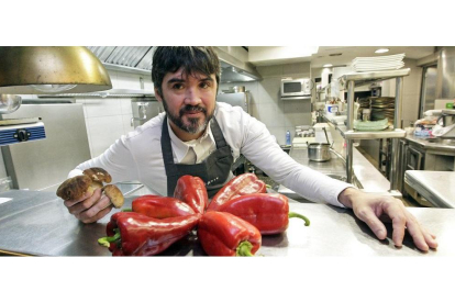 Óscar García posa en la cocina de Baluarte tras una estrella de pimientos y con unos boletus en la mano, un producto que conoce como pocos.-/ LUIS ÁNGEL TEJEDOR