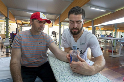 El fisioterapeuta Luis César trabaja el tono muscular de la mano izquierda de Gencho Ivanov para que logre agarrar una botella.-PABLO REQUEJO