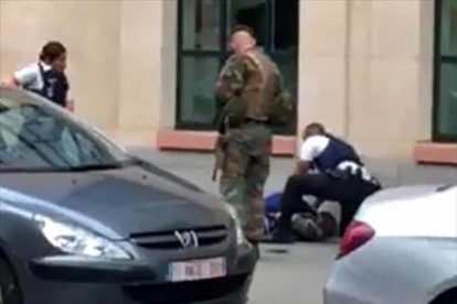 Dos policías y un militar, junto al hombre abatido ayer en Bruselas.-AFP