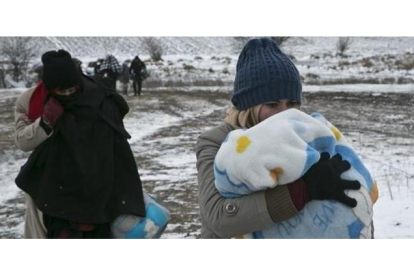 Una mujer migrante protege a su hijo con una manta mientras camina cerca de Miratovac (Serbia), este lunes.-AP / VISAR KRYEZIU
