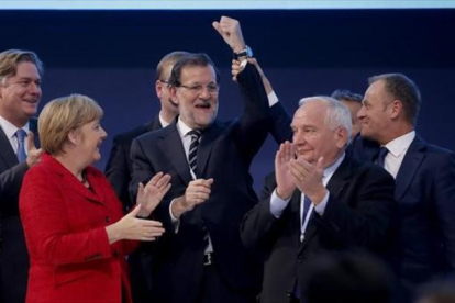 El presidente del Consejo Europeo, Donald Tusk, levanta el brazo de Rajoy en presencia de Angela Merkel y otros dirigentes populares europeos.-AGUSTÍN CATALÁN