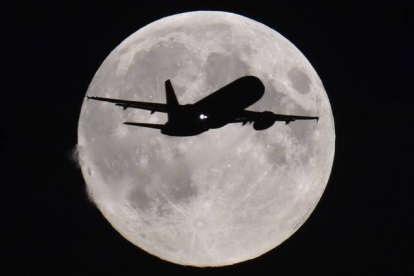 Un avión se acerca al aeropuerto de Heathrow (Londres) con la luna llena al fondo.-Foto: REUTERS / TOBY MELVILLE