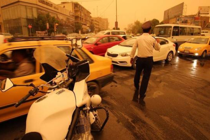 Un policía iraquí organiza el tráfico en Bagdad en medio de una tormenta de arena.-AFP / HAIDAR MOHAMED