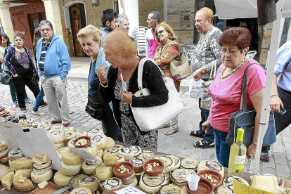 Vecinos y visitantes degustan queso en uno de los expositores del mercado en una anterior edición.-J.M. LOSTAU