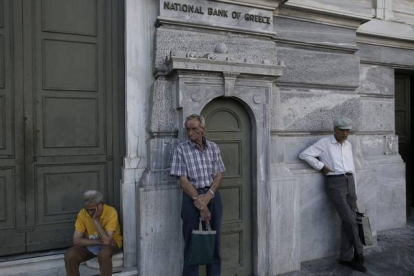 Pensionistas esperan para cobrar frente a un banco de Atenas (Grecia).-Foto:   EFE / YANNIS KOLESIDIS