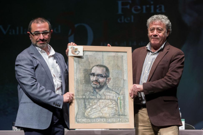 El escritor José Manuel de la Huerga sostiene su retrato junto con el pintor Félix de la Vega.-EL MUNDO