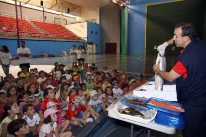 Un pescadero explica a los niños las difentes partes de un pez dentro del Programa Thao contra la obesidad infantil-Ical