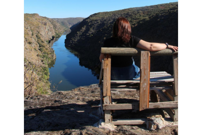 Una mujer disfruta del paisaje del Arribe del Duero sentada en el banco El Hullón.  A la d. indicador  colocado en el  camino.-J.L.C.
