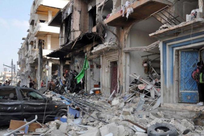 Coches y edificios destruidos cerca del lugar de un doble atentado con bomba en Homs, el 21 de febrero.-EFE