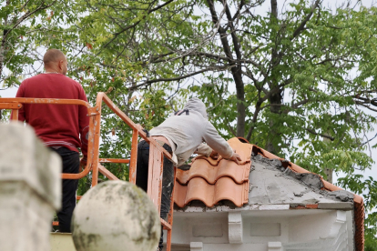 Dos operarios reparan las tejas en la cubierta del edificio. / Miguel Ángel Santos (Photogenic)