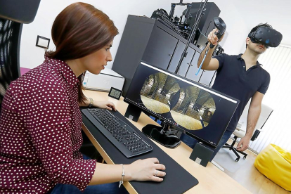 Almudena Cabezas muestra la recreación del túnel de una bodega, mientras que Pablo Sánchez lo contempla desde las gafas de realidad virtual.-J.M.LOSTAU