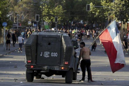 Un manifestante se enfrenta a un vehículo militar durante las protestas en Chile.-AP
