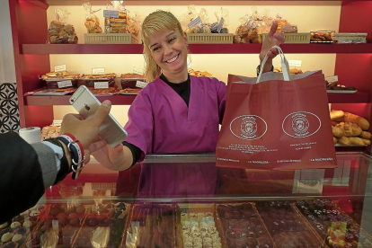 Una trabajadora de la pastelería La Madrileña entrega el lote a un cliente que previamente lo ha reservado a través del móvil.-ENRIQUE CARRASCAL