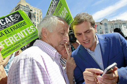 Albert Rivera muestra a un afectado por las preferentes un ‘tuit’ para explicarle lo que escribió sobre el cambio generacional en la política.-J.M. Lostau