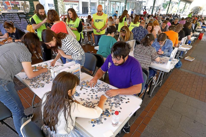 Casi 60 parejas, sentadas para montar un puzle de 500 piezas en menos de dos horas en la Plaza de España.-J.M. LOSTAU
