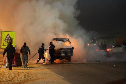 Bomberos egipcios apagan el fuego de varios vehículos que han sido quemados durante los disturbios de este domingo.-Foto: AFP