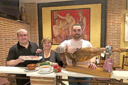 De izquierda a derecha, Jesús Galindo, Pilar Merino y su hijo, Pedro José, en el interior del restaurante La Muralla, delante de uno de los frescos que lo decoran.-ARGICOMUNICACIÓN