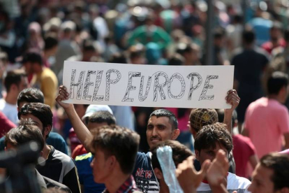 Un inmigrante se manifiesta este jueves en Budapest con una pancarta en la que se lee "Ayúdanos Europa".-AFP / FERENC ISZA