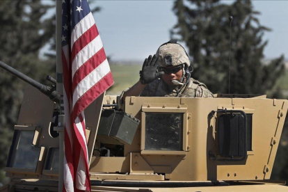 Un soldado de EEUU saluda desde un vehículo blindado en una carretera que conduce a la ciudad de Manbij, al norte de Siria.-HUSSEIN MALLA (AP)
