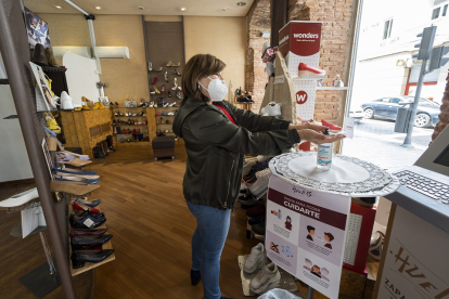 Una mujer se aplica gel desinfectante en una tienda de Valladolid. PABLOREQUEJO