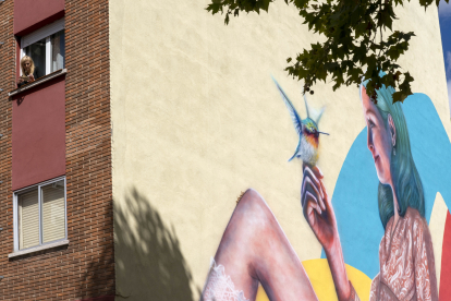 Una mujer con un ave se dibuja en la pared de un edificio de Pajarillos gracias a los 'Murales de la Felicidad'. ICAL