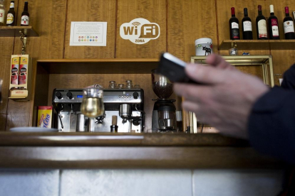Un vecino intenta conectarse a la WiFi gratuita de un bar de un municipio.-EL MUNDO