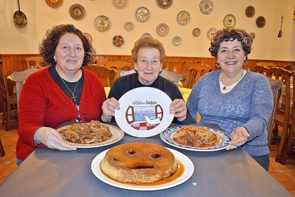 Benilde, entre sus hijas Josefa (con la caldereta) y Ana (con el arroz con botillo), y el flan, en primer término.-ARGICOMUNICACIÓN
