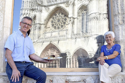 María Luisa Pascual y su hijo José Luis, en uno de los ventanales del Mesón del Cid, donde se refleja la fachada de la Catedral de Burgos.-ARGICOMUNICACIÓN