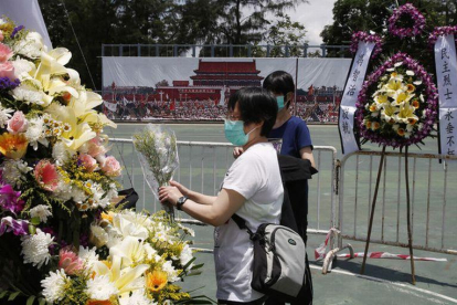 Dos mujeres colocan flores en el memorial a las víctimas de Tiananmen, en Hong Kong.-KIN CHEUNG (AP / KIN CHEUNG)