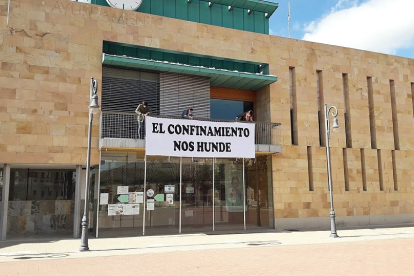 Alfonso Romo coloca la pancarta en el Ayuntamiento. LA 8 DE VALLADOLID