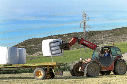 Un agricultor empaca con plástico el trigo verde empleado como forraje, en un municipio palentino.-BRÁGIMO