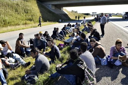 Un grupo de refugiados descansan en medio de una autopista en el sur de Dinamarca.-AP / ERNST VAN NORDE
