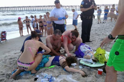 Los servicios de emergencia atienden a la joven de 14 años que ha sido atacada por un tiburón, este domingo en la playa de Oak Island.-Foto:  AP / STEVE BOUSER